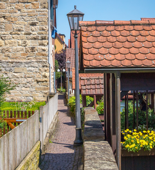 Schmaler gepflasterter Weg zwischen Häusern mit Blumen und Dekorationen. | © Stuttgart-Marketing GmbH, Achim Mende
