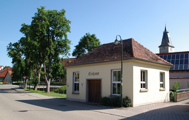 Das Gebäude des historischen Eichamts Blaufelden mit Bäumen und dem Kirchturm im Hintergrund | © Hohenlohe + Schwäbisch Hall Tourismus e. V.