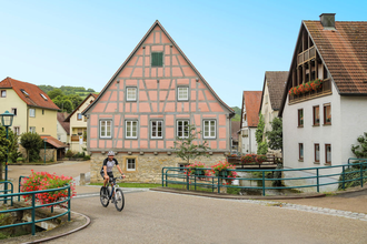 Ein Radfahrer fährt vor dem historischen Fachwerk-Rathaus | © Touristikgemeinschaft Hohenlohe e. V. |  Andi Schmid