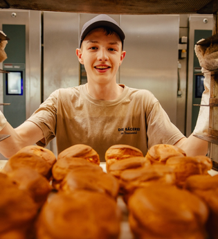 Ein Bäcker zeigt voller Stolz seine Brötchen in der Backstube | © Touristikgemeinschaft Hohenlohe e. V.  | Marc Bauer
