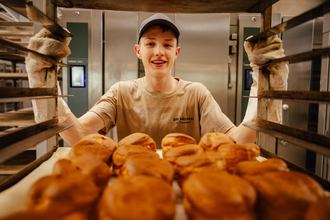 Ein Bäcker zeigt voller Stolz seine Brötchen in der Backstube | © Touristikgemeinschaft Hohenlohe e. V.  | Marc Bauer
