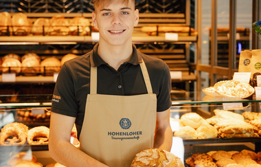 Ein Verkäufer in der Bäckerei hält ein Brot in der Hand | © Touristikgemeinschaft Hohenlohe e. V. | Marc Bauer