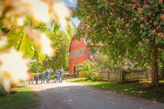 Gruppe von Menschen vor einem historischen Gebäude in Wackershofen, umgeben von blühenden Bäumen. | © © Stadt Schwäbisch Hall - Michael Kühneisen