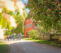 Gruppe von Menschen vor einem historischen Gebäude in Wackershofen, umgeben von blühenden Bäumen. | © © Stadt Schwäbisch Hall - Michael Kühneisen