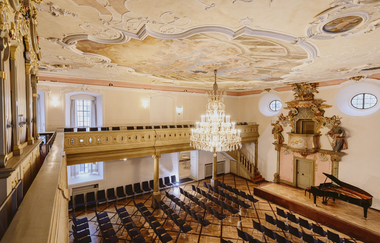 Innenansicht eines prunkvollen Festsaals mit Kronleuchter, Stuckdecke und Flügel. | © NICO KURTH