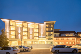 Das Hotel ist nachts hell beleuchtet, davor ist ein Parkplatz für Pkw | © Touristikgemeinschaft Hohenlohe e. V.