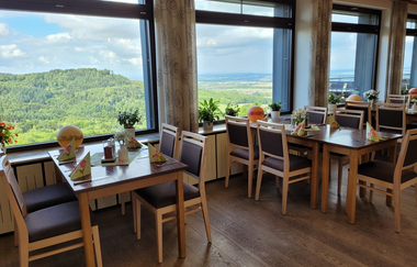 Das Restaurant ist modern mit Holz eingerichtet und hier hat man durch das Fenster Blick ins Grüne. | © Touristikgemeinschaft Hohenlohe e. V. |  Hotel Bergfried