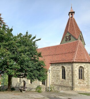 Kirche mit neuem roten Ziegeldach in Eutendorf, umgeben von Bäumen. | © Petra Natzkowski