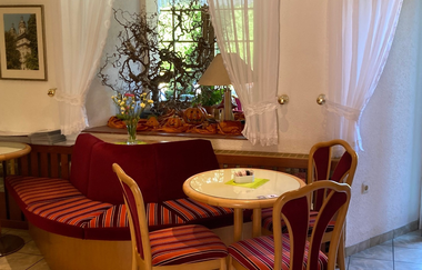 Im Café gibt es eine Eckbank und runde Tische mit rot-gestreiften Stühlen | © Touristikgemeinschaft Hohenlohe e. V. | Klostercafé Schöntal