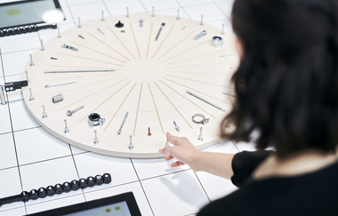 Eine Person steht vor einem Rad mit verschiedenen Schrauben und Muttern | © Touristikgemeinschaft Hohenlohe e. V. | Kocherwerk Haus der Verbindungstechnik