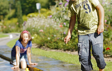 Kinder spielen im Rosenbachlauf mit dem Wasser. Im Bachlauf schwimmen gelbe Gummienten. | © Stadt Bad Mergentheim