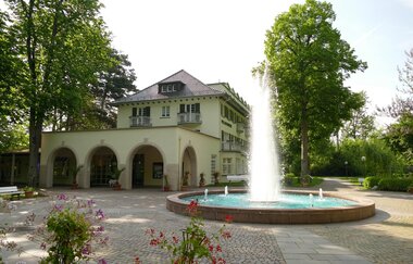 Ein Gebäude der Kurverwaltung, wo sich auch das Haus des Gastes befindet. Vor dem Gebäude steht die große Fontäne. | © Kurverwaltung