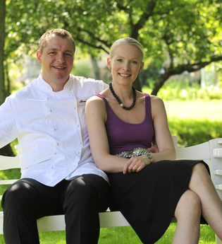 Ein Mann und eine Frau sitzen auf einer weißen Bank und lachen | © Touristikgemeinschaft Hohenlohe e. V.