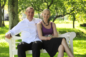 Ein Mann und eine Frau sitzen auf einer weißen Bank und lachen | © Touristikgemeinschaft Hohenlohe e. V.