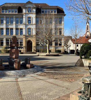 Platz mit Brunnen und Gussfigur vor dem Rathaus