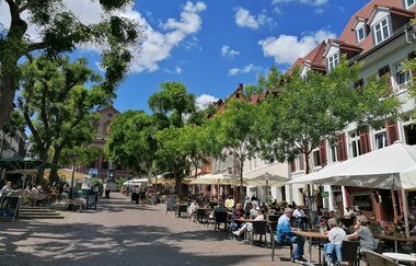 Marktplatz mit Bestuhlung mit blauem Himmel und grünen Bäumen | © Jasmin Wolf