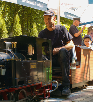 Dampfeisenbahnführer mit Fahrgästen auf Miniatureisenbahn | © Hohenloher Perlen