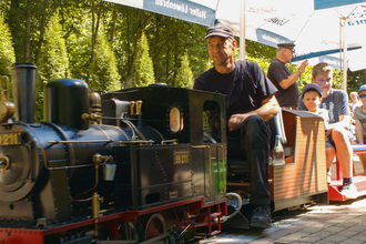 Dampfeisenbahnführer mit Fahrgästen auf Miniatureisenbahn | © Hohenloher Perlen