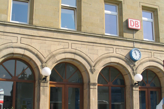 Das Bahnhofsgebäude von außen, hier hängt ein DB-Schild und eine Uhr | © Touristikgemeinschaft Hohenlohe e. V. | Stadt Öhringen