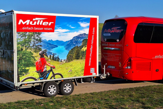 Ein roter Bus zieht einen Fahrradanhänger. | © Müller Reisen Massenbachhausen