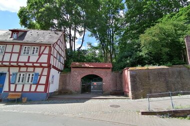 Ein überdachter Torbogen eingebettet zwischen einem Fachwerkhaus und einem Teil der alten Stadtmauer. | © Stadt Weinheim - Jasmin Wolf