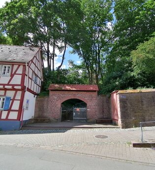 Ein überdachter Torbogen eingebettet zwischen einem Fachwerkhaus und einem Teil der alten Stadtmauer. | © Stadt Weinheim - Jasmin Wolf