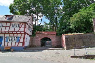 Ein überdachter Torbogen eingebettet zwischen einem Fachwerkhaus und einem Teil der alten Stadtmauer. | © Stadt Weinheim - Jasmin Wolf