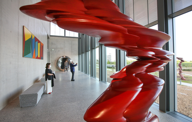 Zwei Besucher bewundern eine rote Skulptur und genießen den Ausblick ins Grüne | © Touristikgemeinschaft Hohenlohe e. V. | Firma Würth