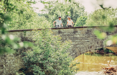 Zwei Fahrradfahrer auf einer alten Steinbrücke. | © Touristikgemeinschaft HeilbronnerLand