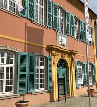 Gebäude des Palais Hirsch in hellrot, gelb und türkis