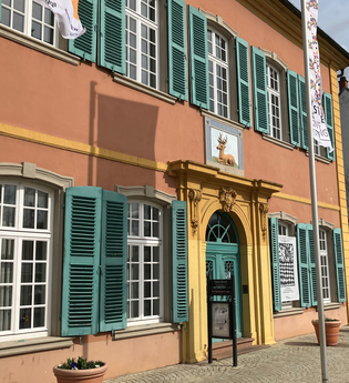 Gebäude des Palais Hirsch in hellrot, gelb und türkis