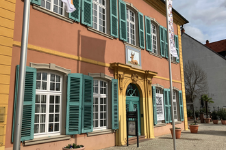 Gebäude des Palais Hirsch in hellrot, gelb und türkis