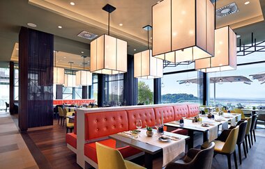 Das Restaurant ist mit roten Sitzbänken und modernen Stühlen und Leuchten ausgestattet | © Touristikgemeinschaft Hohenlohe e. V. |  Panoramahotel Waldenburg – Mellenthin
