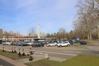 großer Parkplatz an der Astoria Halle mit Autos und E-Rollern