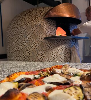 Steinofen mit leckerer Pizza im Vordergrund