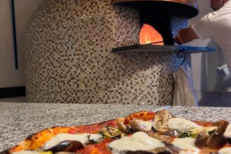 Steinofen mit leckerer Pizza im Vordergrund