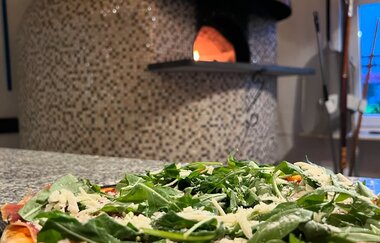 Steinofen mit leckerer Pizza im Vordergrund