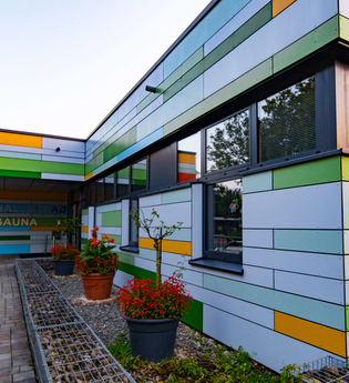 Das Gebäude ist außen mit bunten Wandstreifen gestrichen, davor stehen Blümen | © Touristikgemeinschaft Hohenlohe e. V.  | Stadt Öhringen