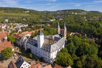 Luftaufnahme vom Residenzschloss Mergentheim. Man sieht den Schlosshof mit den Kirchtürmen, der Schlosspark im Hintergrund | © Björn Hänssler