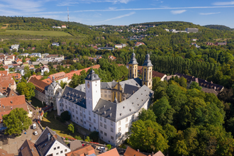 Luftaufnahme vom Residenzschloss Mergentheim. Man sieht den Schlosshof mit den Kirchtürmen, der Schlosspark im Hintergrund | © Björn Hänssler