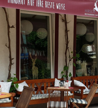 Außenbereich eines Cafés mit Holzmöbeln und Pflanzen. | © Restaurant Café Hirsch