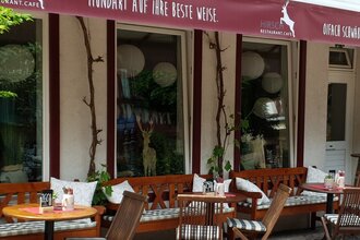 Außenbereich eines Cafés mit Holzmöbeln und Pflanzen. | © Restaurant Café Hirsch