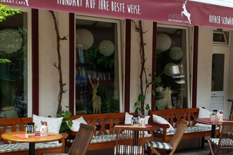 Außenbereich eines Cafés mit Holzmöbeln und Pflanzen. | © Restaurant Café Hirsch