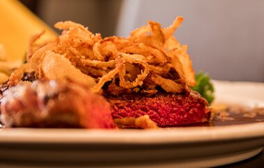 Nahaufnahme eines Steaks mit Röstzwiebeln auf einem Teller. | © Restaurant Café Hirsch