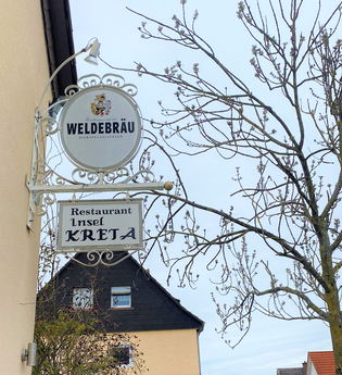 Schilder des Restaurants neben Baum