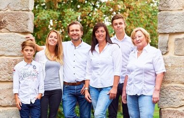 Drei Frauen, zwei Männer und ein Jugendlicher stehen unter einem Steintor | © Touristikgemeinschaft Hohenlohe e. V. | Weingut Schneckenhof Müller