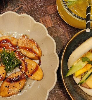 Veganer Teller mit Teigtaschen, Bao Bun und Getränk. | © SMG