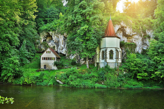 Die Wallfahrtskapelle steht am Fluss Jagst mit einer aufragenden Tuffsteinfelsenwand dahinter | © Touristikgemeinschaft Hohenlohe e. V. | Andi Schmid