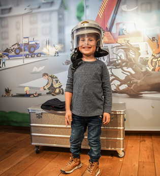 Kind mit Feuerwehrhelm in der BLAULICHT Ausstellung | © Stadtmuseum Neckarsulm