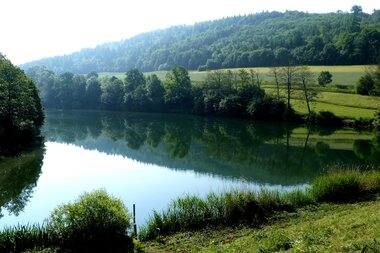 Stausee mit grünen Wiesen | © Touristikgemeinschaft Hohenlohe e. V. | Gemeinde Mulfingen